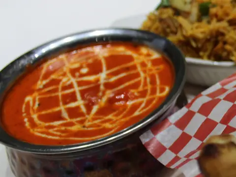 Butter chicken in a steel bowl with a swirl of cream